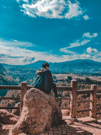 Man photographing on rock against sky