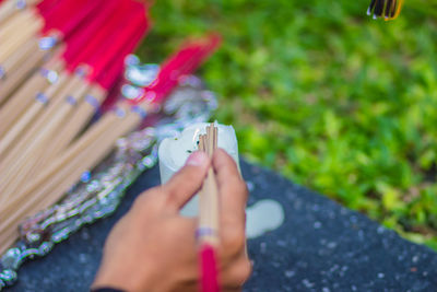 Cropped hand burning incense sticks with candle on table