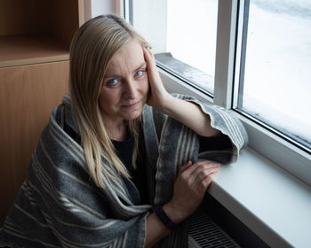 Young woman looking through window