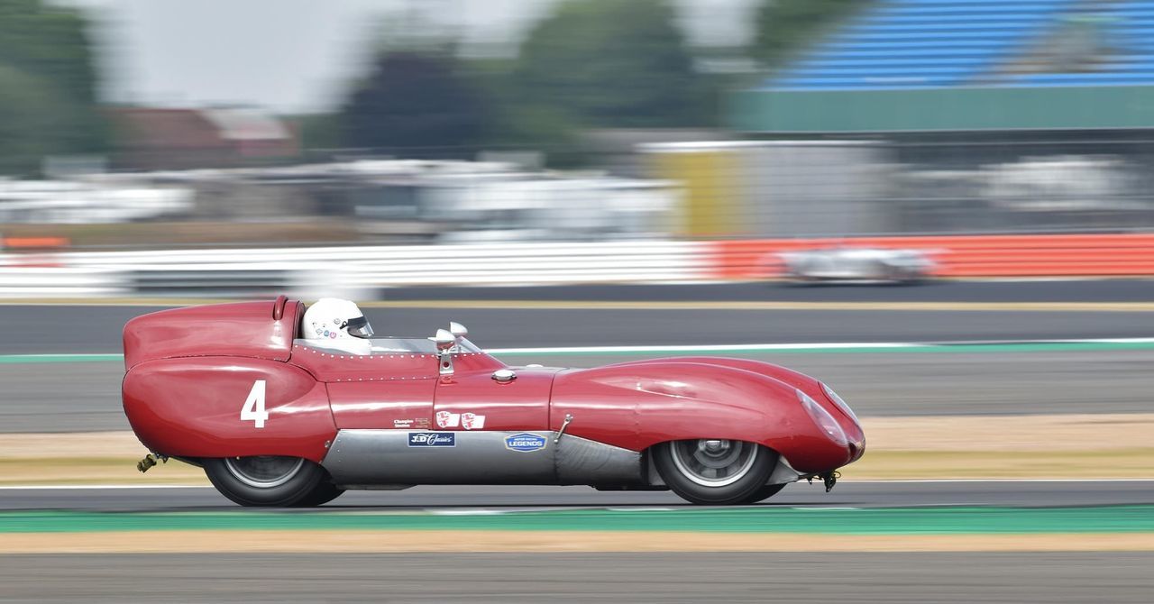 transportation, mode of transportation, speed, motion, blurred motion, land vehicle, car, motor vehicle, day, red, road, on the move, city, street, no people, side view, competition, sports race, outdoors