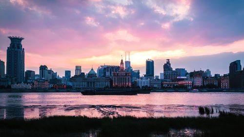 River by buildings against sky during sunset