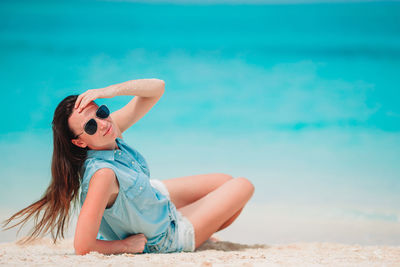 Woman wearing sunglasses sitting on beach