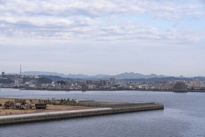 View of buildings by river against cloudy sky