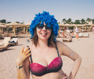 Portrait of smiling young woman in wig at beach against sky