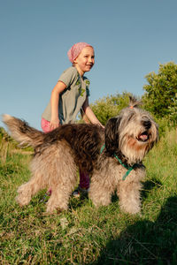 Little girl hugging playing with dog walking spending time together. child with pet in summer meadow