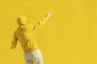 Rear view of man standing against yellow wall