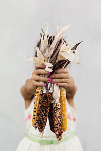 Close-up of woman holding bouquet against white background