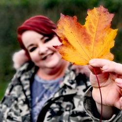 Close-up of woman holding maple leaf during autumn