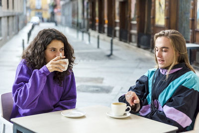 Friends drinking coffee while sitting at outdoors.