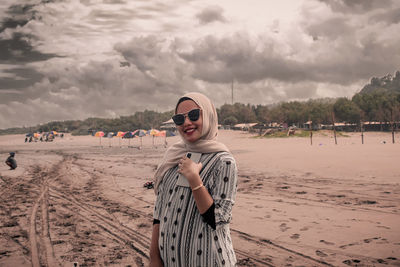 Portrait of smiling young woman standing on beach