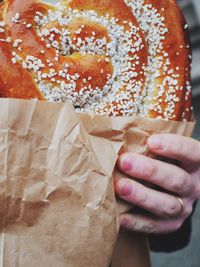 Cropped image of hand holding pretzel with wax paper