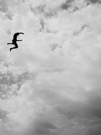 Low angle view of birds flying against cloudy sky