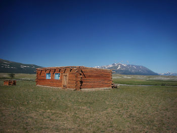 Built structure on field against clear blue sky