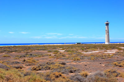 Lighthouse on land against blue sky