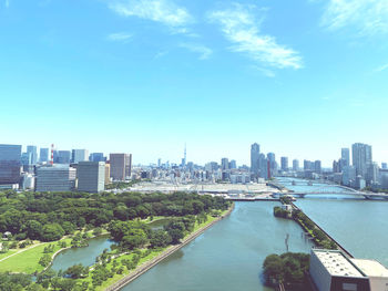 Modern buildings by river against sky in city