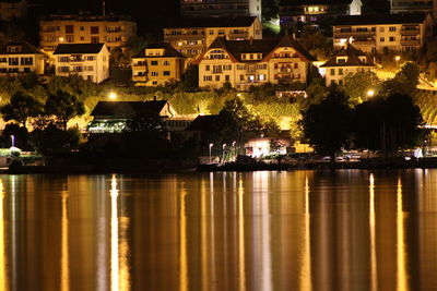 Illuminated buildings by river in city at night