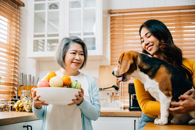 Portrait of young woman with dog sitting at home