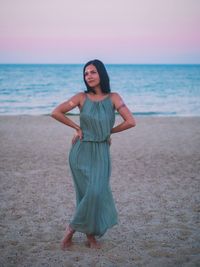 Full length of young woman standing at sandy beach