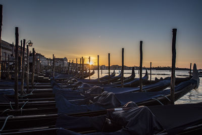 Boats moored at canal against sky during sunset