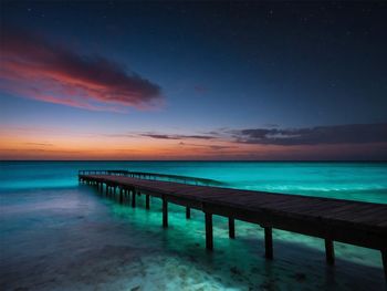 Pier over sea against sky during sunset