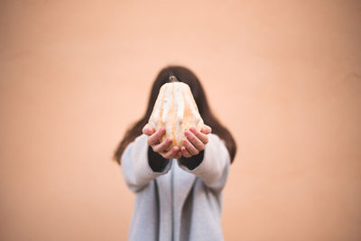 Midsection of woman holding ice cream against wall