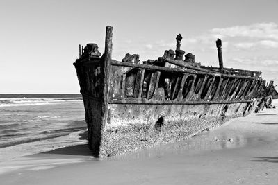 Abandoned boat on beach against sky