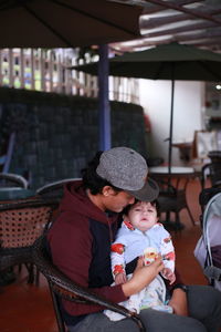 Father and son sitting on seat at restaurant