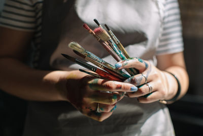 Midsection of woman holding paintbrushes