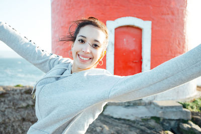 Portrait of smiling young woman standing against wall