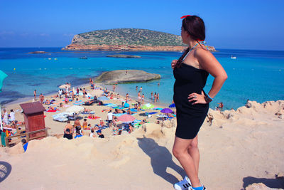 Rear view of woman on beach against sky