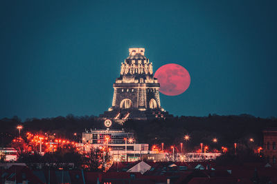 Illuminated buildings in city against clear sky at night