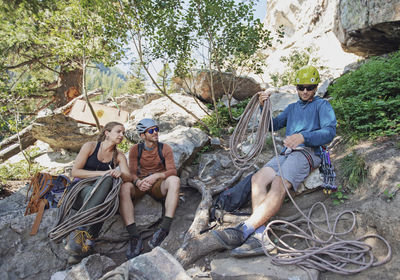 Three people prepare rock climbing gear below cliff in wyoming