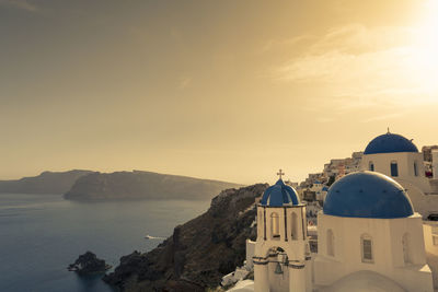 Church at coastline in santorini against sky during sunset