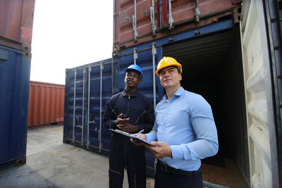 Men standing against cargo container