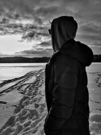 Rear view of man standing at beach against sky