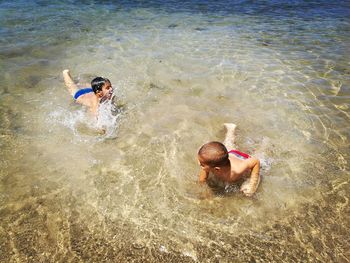 High angle view of shirtless brothers swimming on shore