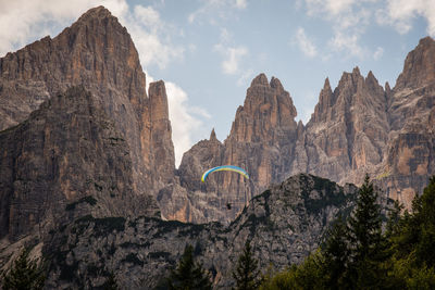 Low angle view of person paragliding against rock mountain