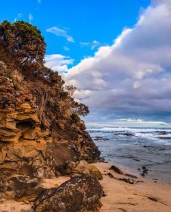 Rock formation on beach against sky