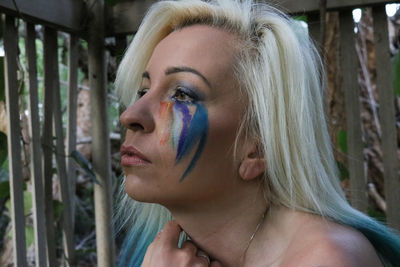 Close-up of thoughtful woman with face paint looking away by fence