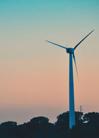 Low angle view of wind turbine against sky during sunset