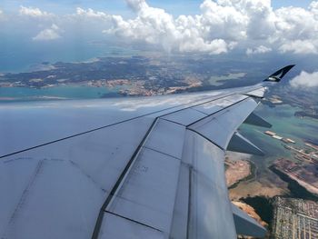 Aerial view of airplane wing over sea against sky