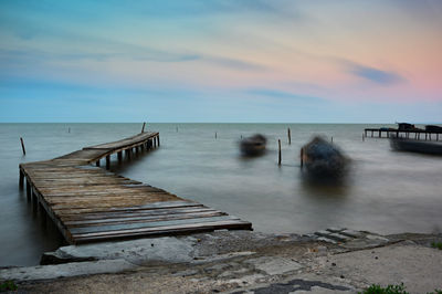 Pier over sea against sky during sunset