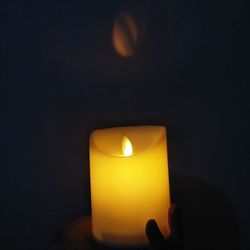 Close-up of lit tea light candle in darkroom