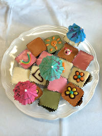 Directly above shot of colorful cake slices and drink umbrellas on plate