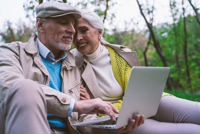 Man using mobile phone while sitting on laptop