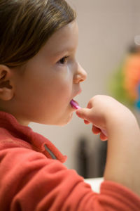 Close-up portrait of girl brushing teeth at home