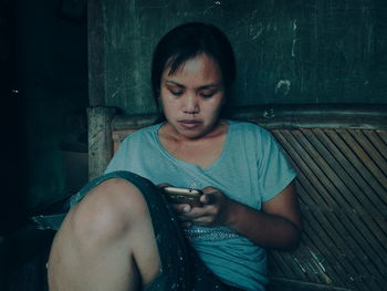 Mid adult woman using mobile phone while sitting at home