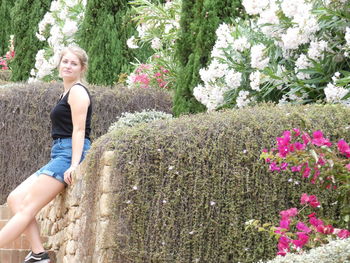 Woman standing by flowering plants against trees