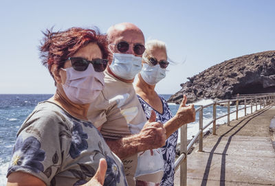 Portrait of senior friends by sea against sky