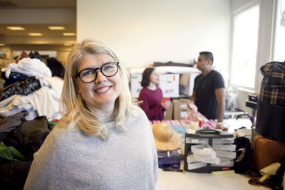 Portrait of smiling woman standing against volunteers talking in background